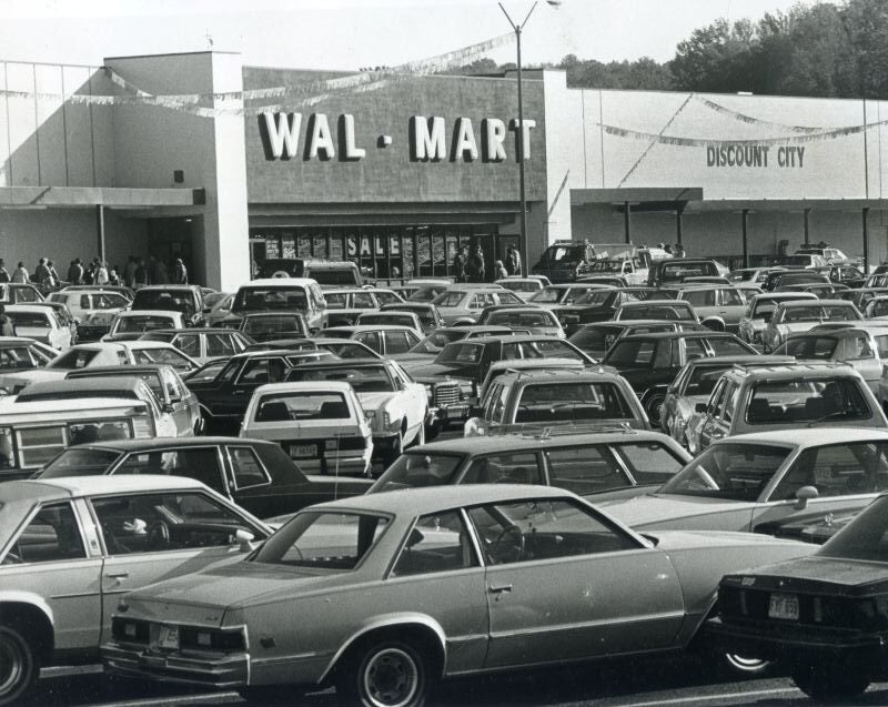 Black-and-white photo of a crowded Wal-Mart Discount City parking lot